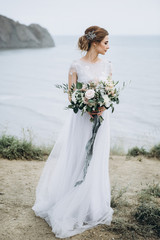Pretty bride with wedding flowers by the sea