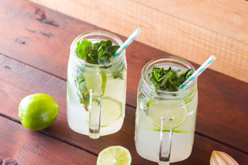 Mojito and mint on wooden background. Refreshing cocktail with lime and fresh mint on wooden...