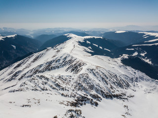 Fototapeta na wymiar winter landscape with the mountain peaks covered by snow and clouds. aerial view by drone. romanian mountains, Negoiu peak, Fagaras Mountains