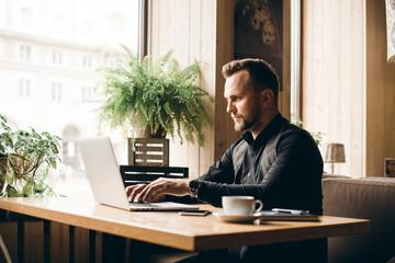 Obraz premium Young man drawing template for the web site associated with digital marketing, current trends and tendencies of UX / UI design. Businessman who rules his company remotely, like a freelancer