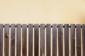 spaced picket brown wooden fence on beige background