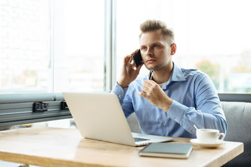 Stylish young man calling by the phone to solve business problems. Online consultation by phone. Freelancer discussing the development and planning of his online project. Outsourcing. Mobile services.
