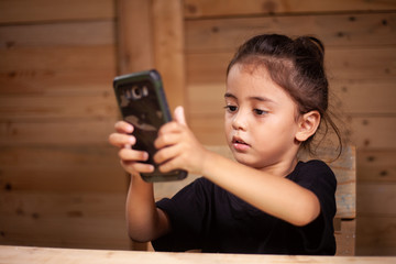 a boy wear black tee shirt watching his mobile in wooden room
