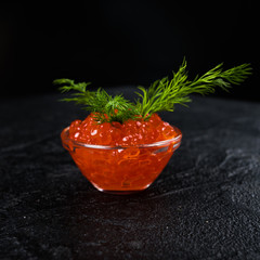 Red Caviar in bowl over black background