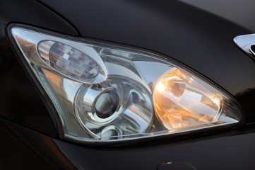 Obraz na płótnie Canvas headlight of the main light of the black car, close-up.