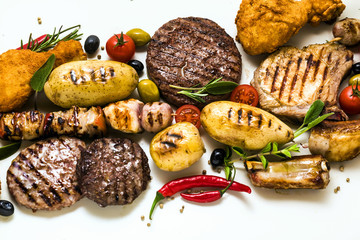 BBQ meat party with different types of meat: beef burgers, pork ribs, turkey meatballs, chicken thighs breaded with potatoes and tomatoes, spices and aromatic herbs. Summer menu for gourmets, rest