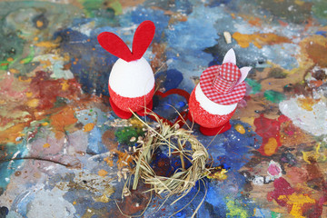 Easter red and white bunny eggs on colorful old artistic palette