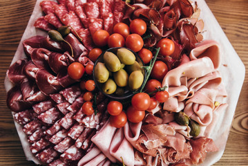 Meat plate with various cuts of meat delicacies, olives and tomatoes