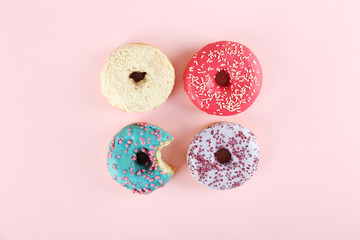 Vibrant composition of lush donut with colorful sprinkled icing, on bright background with a lot of copy space for text. Tasty but unhealthy food concept. Close up, flat lay, top view.