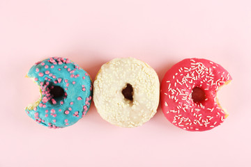 Vibrant composition of lush donut with colorful sprinkled icing, on bright background with a lot of copy space for text. Tasty but unhealthy food concept. Close up, flat lay, top view.