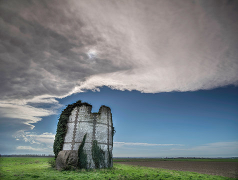 View of ruined windmill against cloudy sky