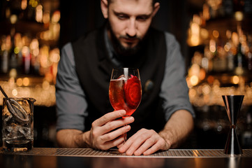 Red cocktail in glass in bartender's hands