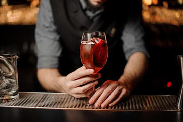 Red cocktail in glass in bartender's hands