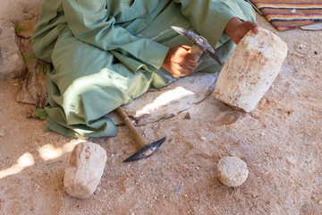 Stone carver working with hammer at alabaster column