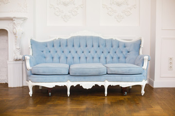 light classic royal interior with blue soft sofa with fabric upholstery. Elegant royal luxury interior with white walls and blue sofa