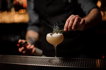Foto op Plexiglas Bartender adds rosemary in alcohol light brown cocktail © fesenko