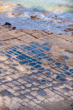 Waves lap up against tessellated pavement