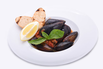 mussels in a plate in tomato sauce with lemon and toast on a white plate