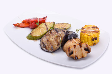  grilled vegetables on a white plate - eggplant, zucchini, champignons, corn and red sweet pepper