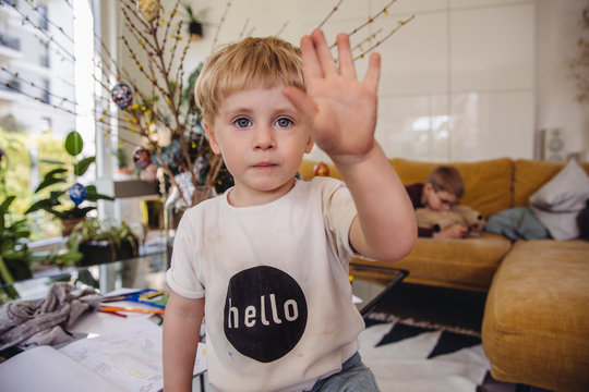 Boy at home holding up hand to say hello