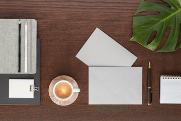 Obraz na płótnie Canvas workspace notepad notes pen pencil coffee envelope leaf monstera top view with copy space for your text. flat lay. 