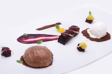  delicious sweets - chocolate cake, fruit candies and ice cream balls on a white plate