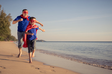 Father and son playing superhero on the beach at the day time.