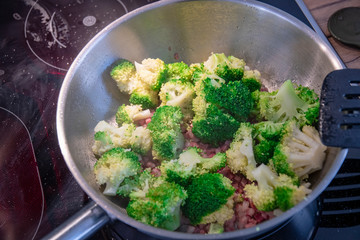 Broccoli is fried in hot oil with bacon cubes