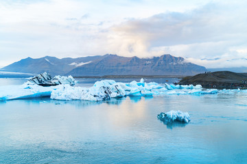 Luminous blue icebergs  floating in Jokulsarlon glacial lagoon with background of glacier mountain. South Iceland, VatnajÃ¶kull National Park. Copy space background. Place for text.