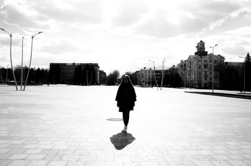 Street photography. Silhouette of a girl in the town square on a bright sunny day in the city
