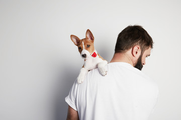Handsome bearded man snuggling and hugging his basenji puppy dog, close friendship against a white background. Copy paste space mock-up