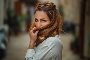 Portrait of beautiful, young, stylish Women Tourist Traveler playing with her Hair in the Streets of Bari, Italy. Street fashion. Holliday, Travel Concept.