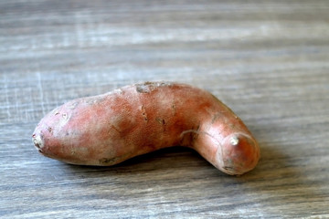 Raw sweet potato on a wooden table. Selective focus.