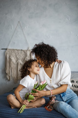 Happy Women's Day! Mom and daughter tulips. Mom and girl are smiling with braces of African-American appearance.