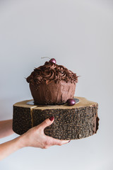 Woman holding a chocolate cake on a wooden plate, close up. Delicious bakery And provide high calorie