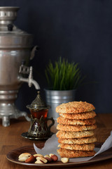 Pile Oatmeal Cookies with nuts and black tea at Samovar on a wooden table. Dark background. Copy space