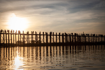 Obraz premium Sunset over U Bein Wooden bridge with locals' and tourists' silhouettes, Mandalay, Myanmar