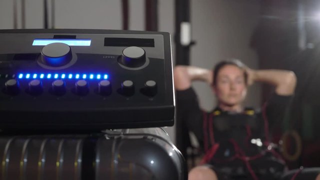 EMS electro stimulation sports equipment in gym. Woman doing exercises