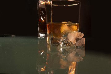 Glass with Whiskey and ice inside adorned next to it with an ice cube in the shape of a skull skull that elegantly reflect the composition in a whiskey glass base for Scotland and for the world with i