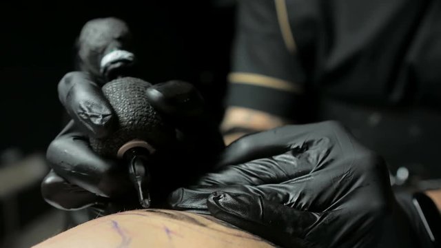 Tattoo artist makes a tattoo on a man's hand