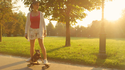 LENS FLARE: Cheerful girl and cute puppy riding a high tech electric longboard.