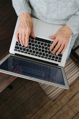 Fototapeta na wymiar Hands of elderely woman, browsing on her laptop
