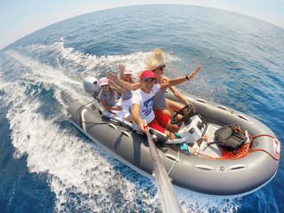 Naklejka premium family with children sailing on an inflatable motorboat in the sea