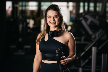 A young woman taking a break at the gym with a bottle of water or energy drink