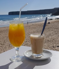 Freshly squeezed orange juice and a glass of latte in a small beach bar overlooking the sea