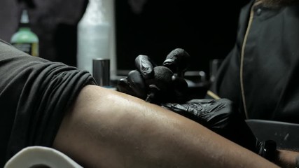 Tattoo artist makes a tattoo on a man's hand