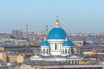Fototapeta na wymiar Trinity Cathedral with a blue dome and gold stars on the background of roofs in the city of St. Petersburg.