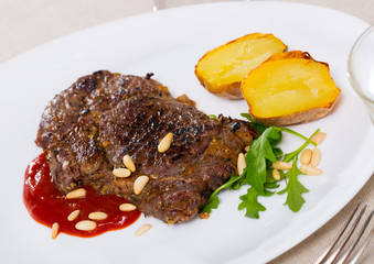 Well done roasted beef steak with ketchup and pine nuts