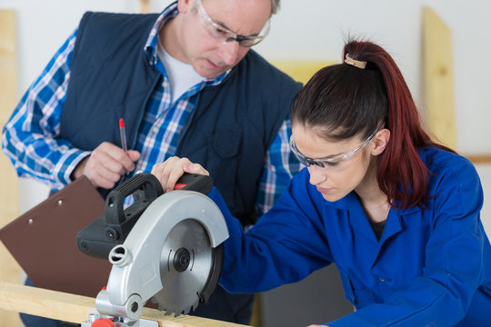 student and teacher in carpentry class using circular saw