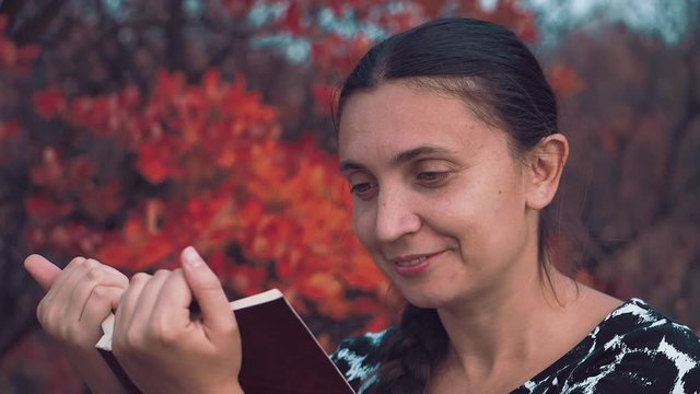 The girl of European appearance conducts an orchestra of trees and leaves of the autumn forest Girl of the European appearance stands face to the autumn forest in the headphones and conducting the orc